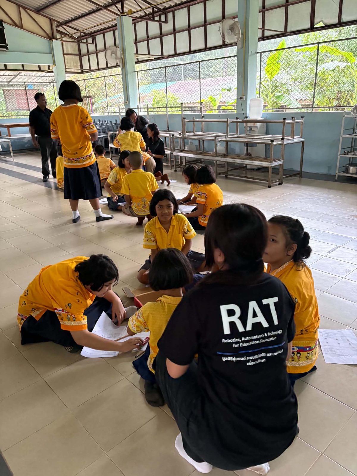 Students working through logic worksheets with a RAT Foundation volunteer
